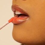 close up of woman applying lip gloss