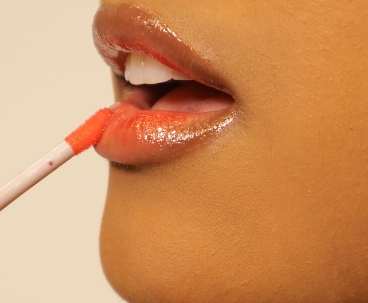 close up of woman applying lip gloss
