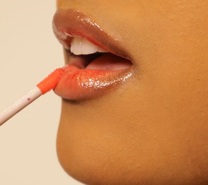 close up of woman applying lip gloss