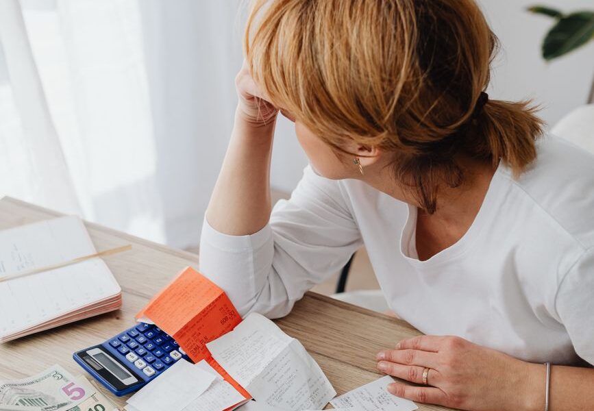 woman sitting next to a laptop with bills and monkey on the table