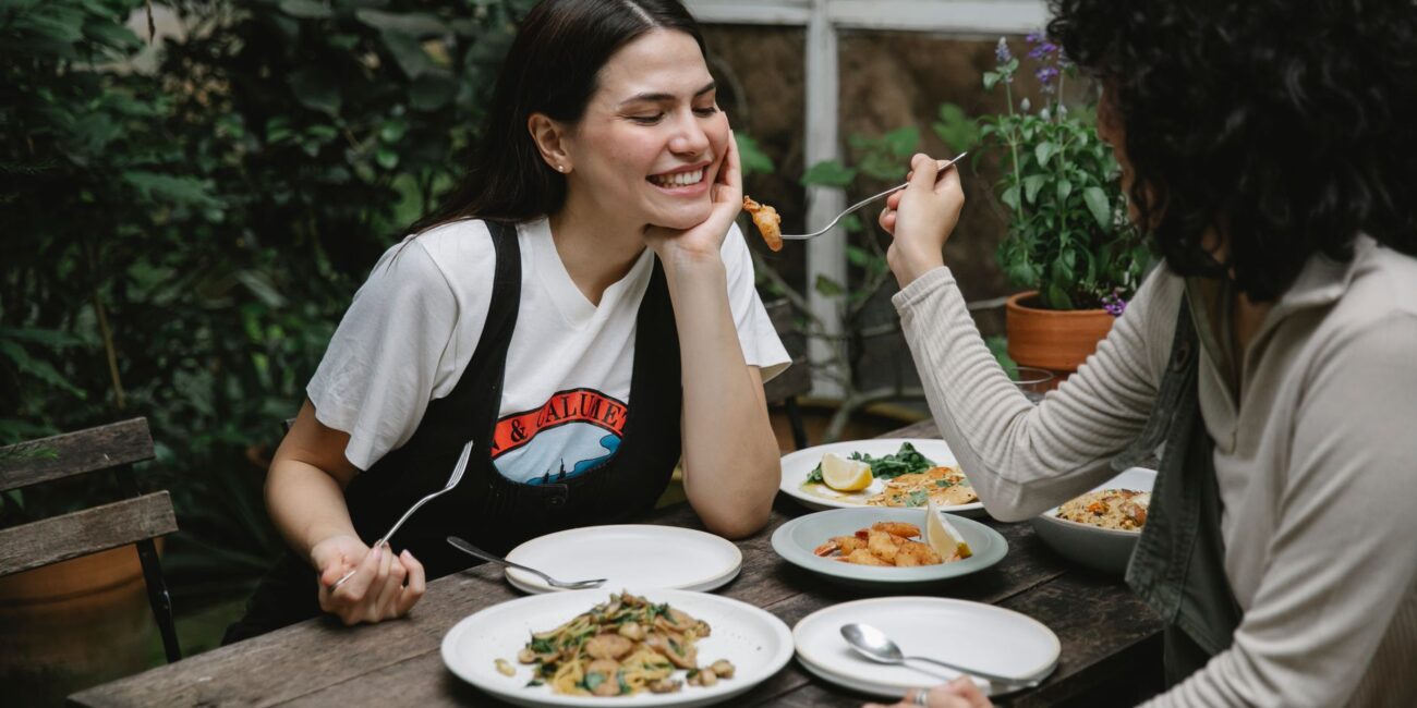 woman feeding girlfriend with fried seafood in garden