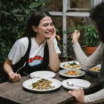 woman feeding girlfriend with fried seafood in garden