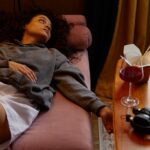 a woman lying near a glass of wine