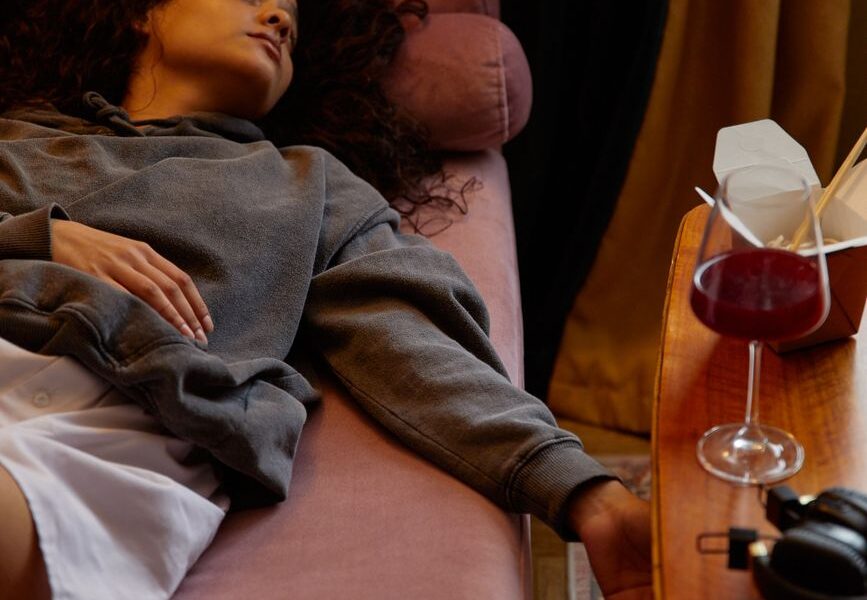 a woman lying near a glass of wine