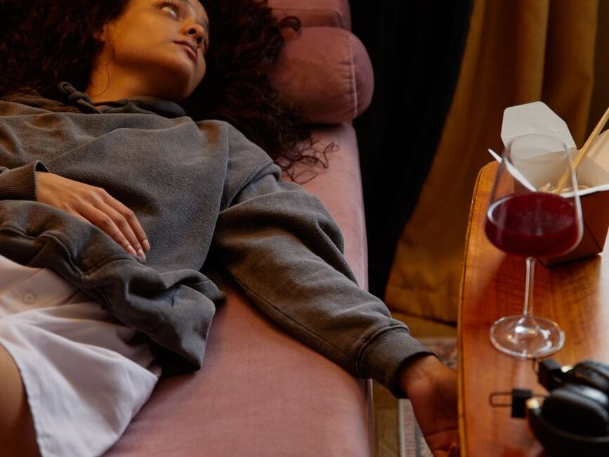 a woman lying near a glass of wine