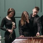 a man and women standing beside a coffin
