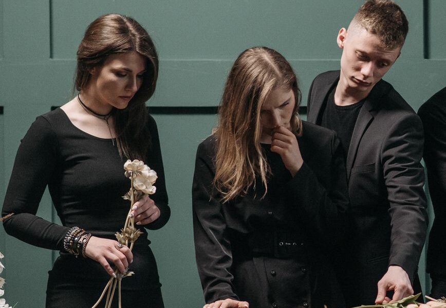 a man and women standing beside a coffin
