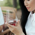 woman in white shirt holding clear wine glass