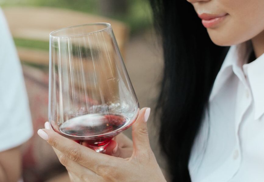 woman in white shirt holding clear wine glass