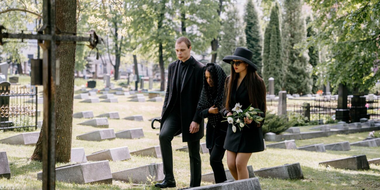 a man and two women in black clothes in a cemetery