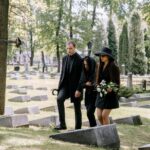 a man and two women in black clothes in a cemetery