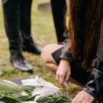 a close up shot of a person putting flowers on a headstone