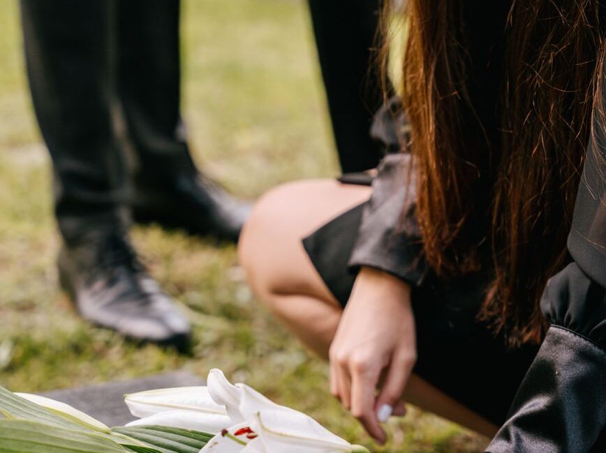 a close up shot of a person putting flowers on a headstone